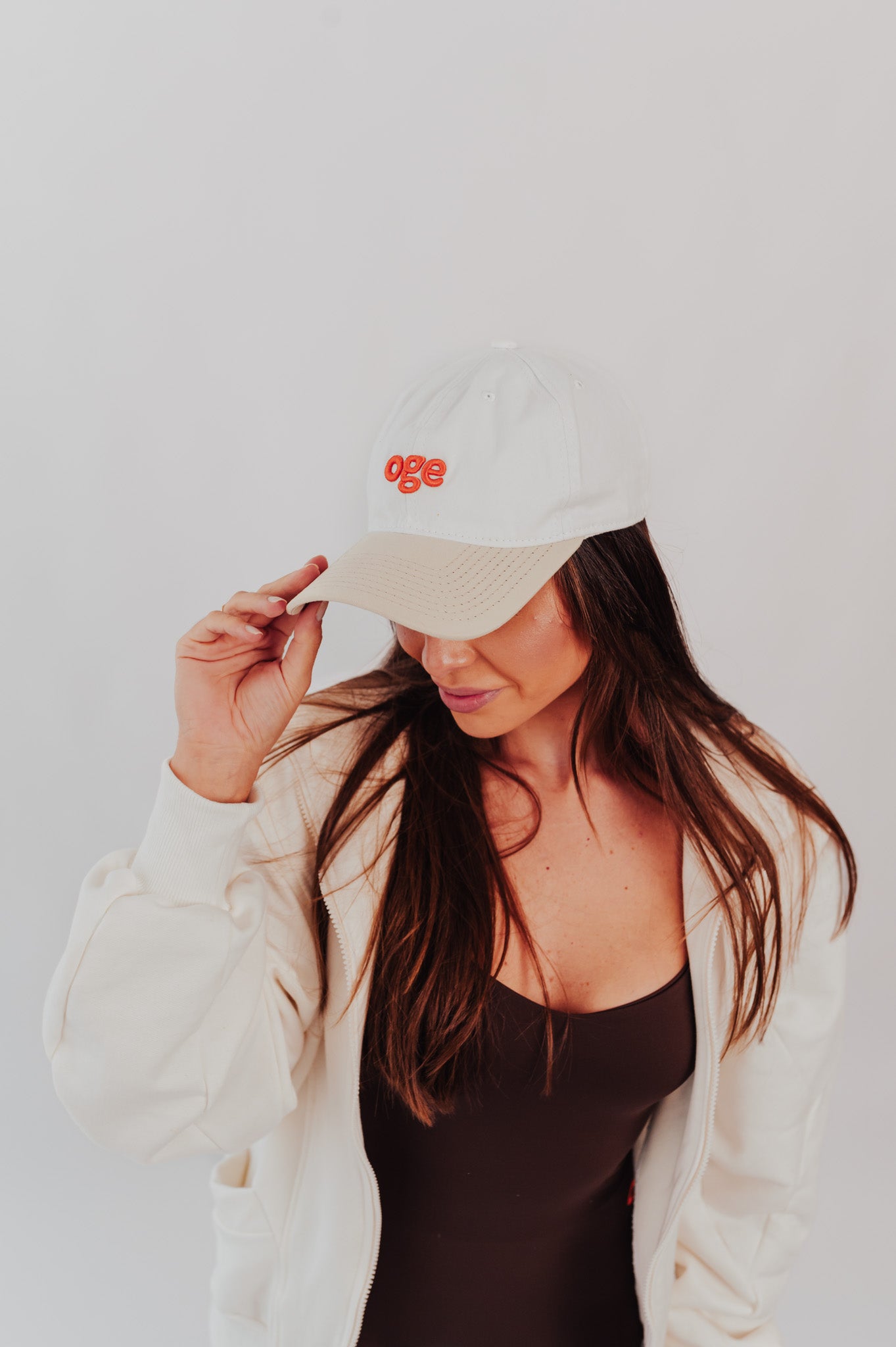 Modelo ajustando o Boné OGE branco com logo laranja