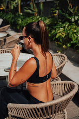 Mulher de top preto tomando café em uma mesa ao ar livre